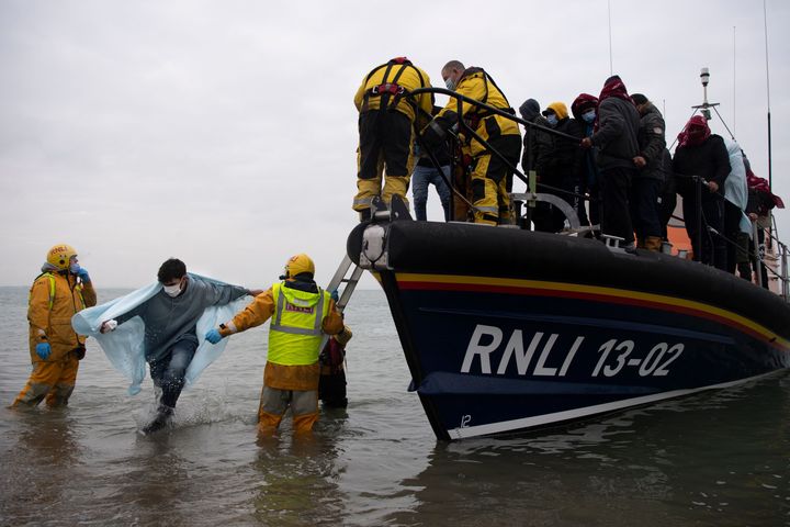 Migrants are helped ashore from a Royal National Lifeboat Institution lifeboat at a beach in Dungeness, on the south-east coast of England, on Wednesday after crossing the English Channel.