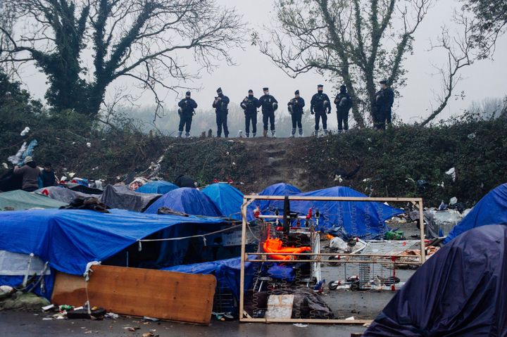 Police forces oversee migrants' makeshift camp in Grande-Synthe, northern France, on Nov. 16. French police were evacuating migrants from the makeshift camp near Dunkirk where at least 1,500 people gathered in hopes of making it across the English Channel to Britain.