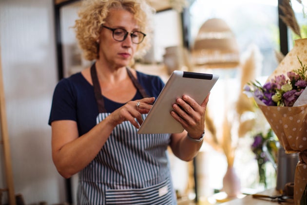 Blond florist with glasses working on a digital tablet