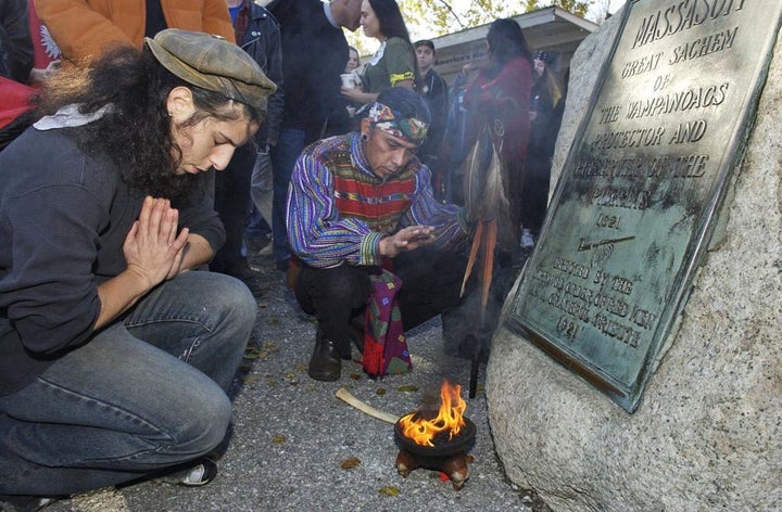 FILE- Supporters of Native Americans pause following a prayer during the 38th National Day of Mourning at Coles Hill in Plymouth, Mass., on Nov. 22, 2007. Denouncing centuries of racism and mistreatment of Indigenous people, members of Native American tribes from around New England will gather on Thanksgiving 2021 for a solemn National Day of Mourning observance.