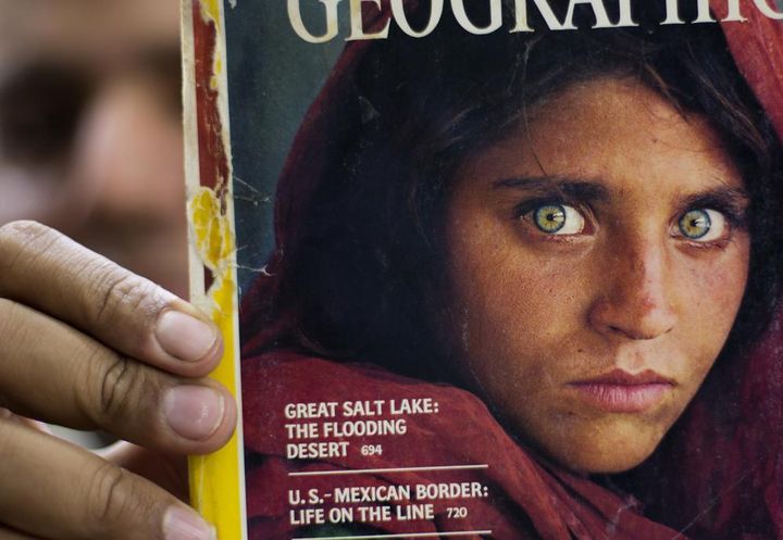 In this file photo from Oct. 26, 2016, Pakistan's Inam Khan shows a copy of a magazine with the photograph of Afghan refugee woman Sharbat Gulla, from his rare collection in Islamabad, Pakistan. 