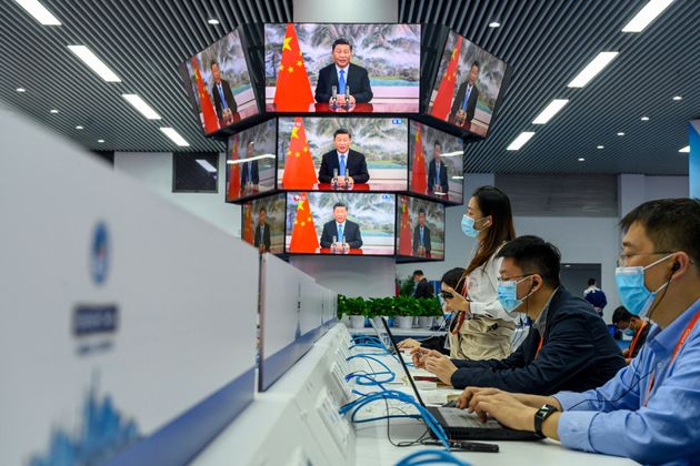 Media staff work next to screens showing live images of China's President Xi Jinping speaking during the opening ceremony of the China International Import Expo (CIIE), at the media center of the CIIE in Shanghai on November 4, 2021. - China OUT (Photo by AFP) / China OUT (Photo by STR/AFP via Getty Images)