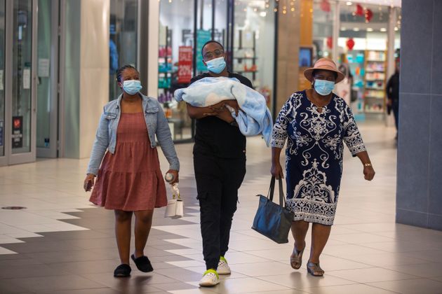26 Νοεμβρίου, Γιοχάνεσμπουργκ, Νότια Αφρική. Μία οικογένεια με μάσκες στα πρόσωπα σε εμπορικό κέντρο. (AP Photo/Denis Farrell)