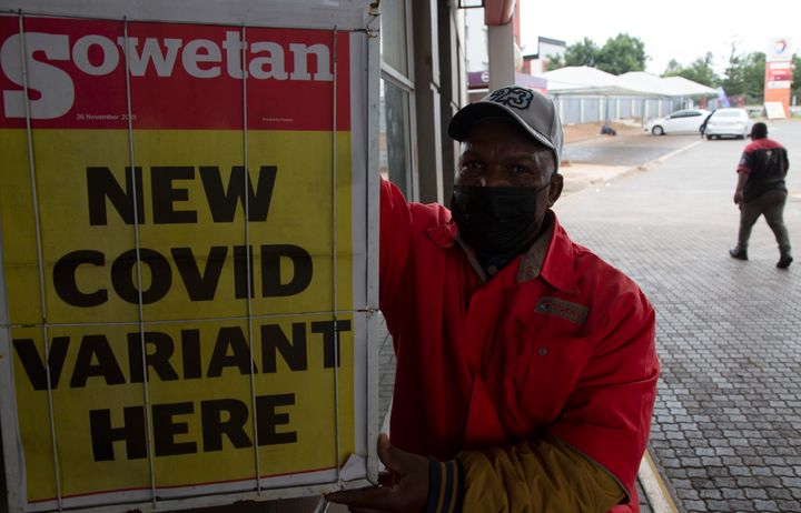 A petrol attendant stands next to a newspaper headline in Pretoria, South Africa, Saturday, Nov. 27, 2021. As the world grapples with the emergence of the new variant of COVID-19, scientists in South Africa — where omicron was first identified — are scrambling to combat its spread across the country. (AP Photo/Denis Farrell)