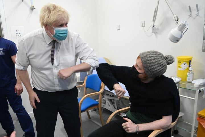 Britain's Prime Minister Boris Johnson (L), wearing a face covering to combat the spread of COVID-19, greets a member of the public waiting to receive the vaccine, during his visit to Lordship Lane Primary Care centre in north London on November 30, 2021, to promote the NHS vaccine booster campaign. (Photo by PAUL GROVER/POOL/AFP via Getty Images)