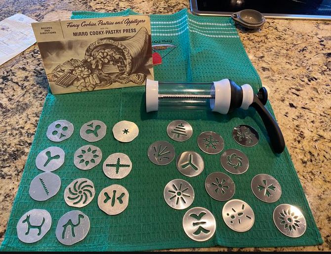 A cookie press with a collection of vintage and modern discs.