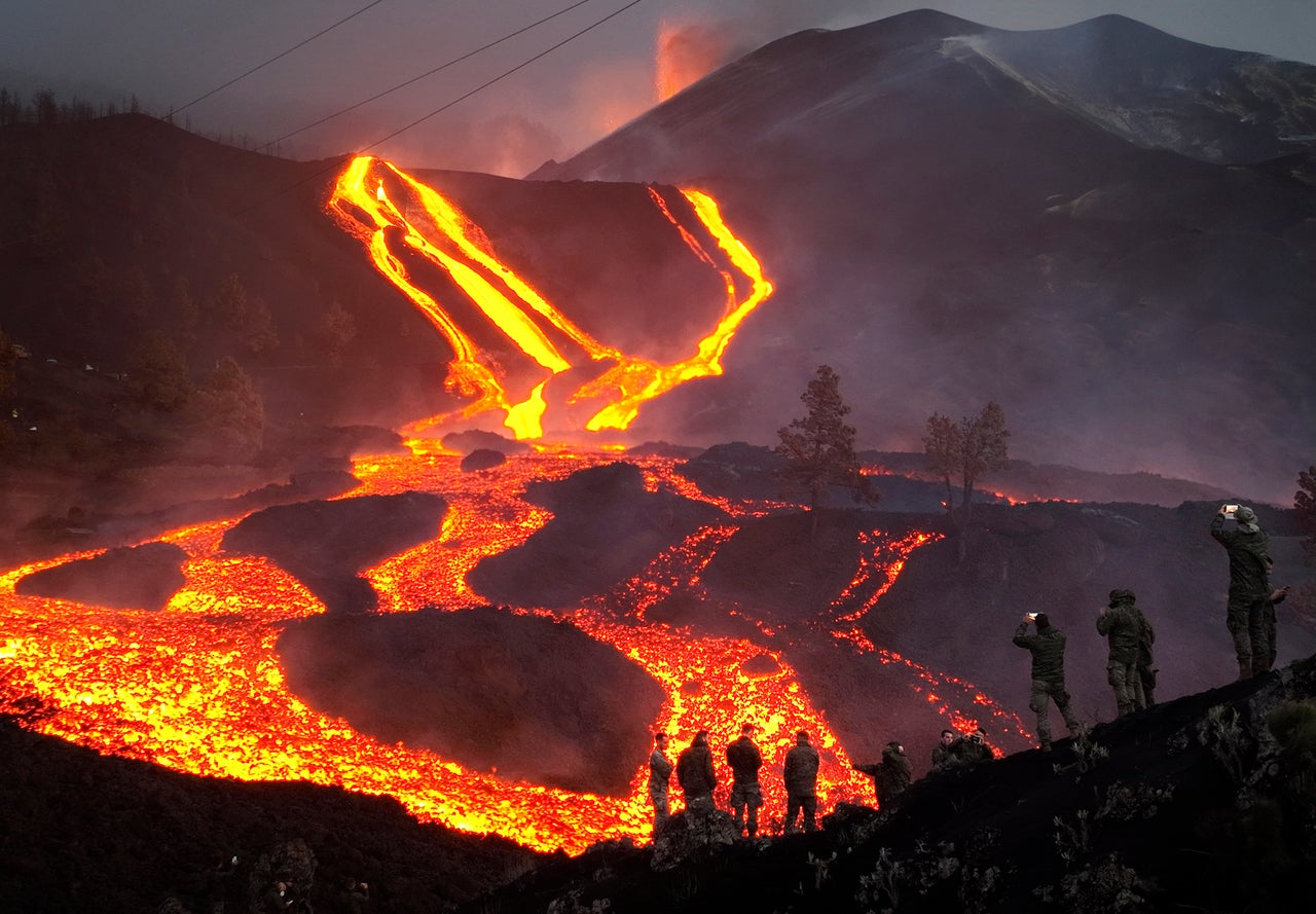 Spanish Army soldiers stand on a hill as a volcano continues to erupt on the Canary island of La Palma on Monday. Several new volcanic vents opened in La Palma on Sunday, releasing new lava that flowed fast down a ridge and threatened to widen the impact on evacuated land, infrastructure and homes.