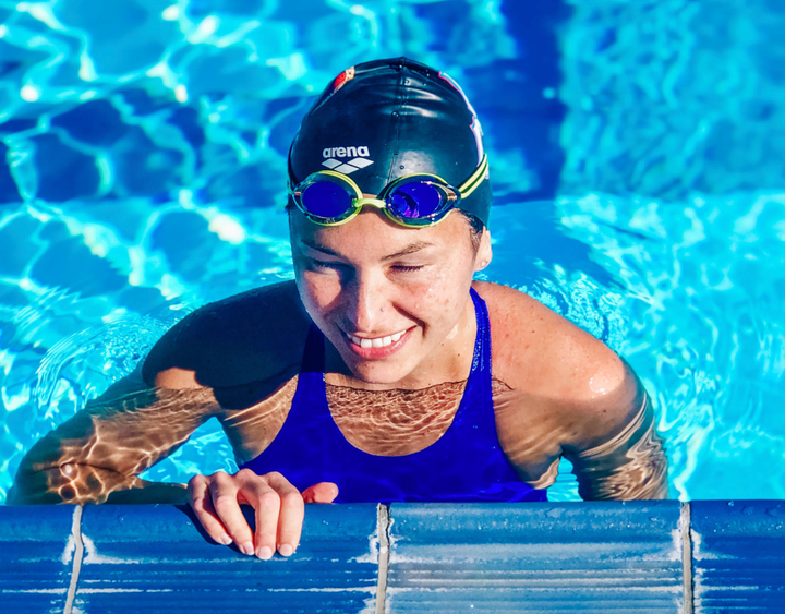 The author holding the wall with one arm while warming up at a U.S. Paralympic swimming competition.