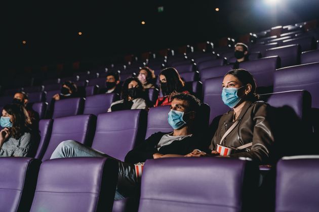 People in a movie theater during Covid-19 coronavirus pandemic. Focus on a millennial