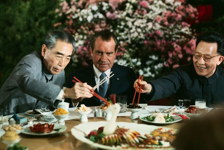 (Original Caption) President Nixon holds his chopsticks in the ready position as Premier Chou En-lai (left) and Shanghai Communist Party leader Chang Chun-chiao reach in front of him for some tidbits at the beginning of the farewell banquet here.