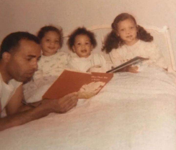 The author (far right) and her sisters, Karina (left) and Suzette, listening to their dad read a bedtime story in 1969.
