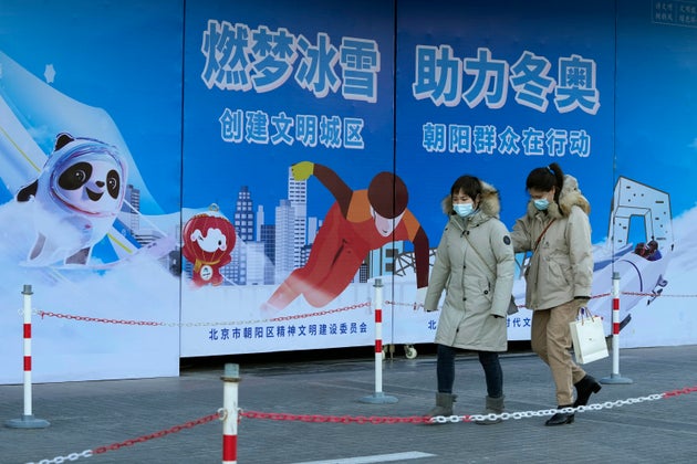 Residents wearing masks pass by propaganda boards promoting the upcoming Beijing Winter Olympics in Beijing, China, Monday, Nov. 22, 2021. Beijing reiterates its commitment to hosting a frugal and green Winter Olympics ahead of the February sporting event, promising to make the games