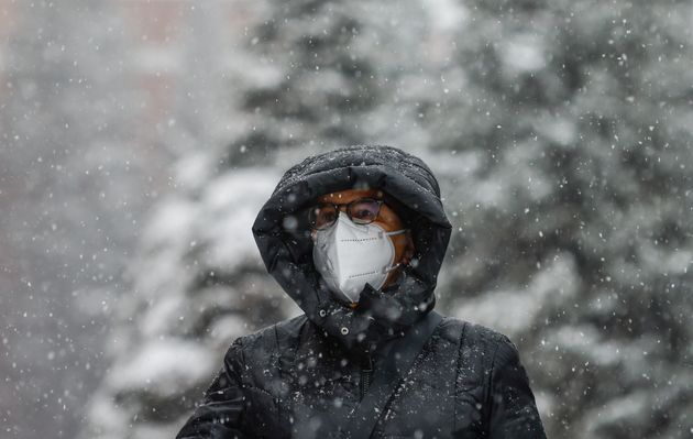 Γυναίκα με προστατευτική μάσκα προσώπου περπατά στην Κόκκινη Πλατεία κατά την διάρκεια της έντονης χιονόπτωσης.