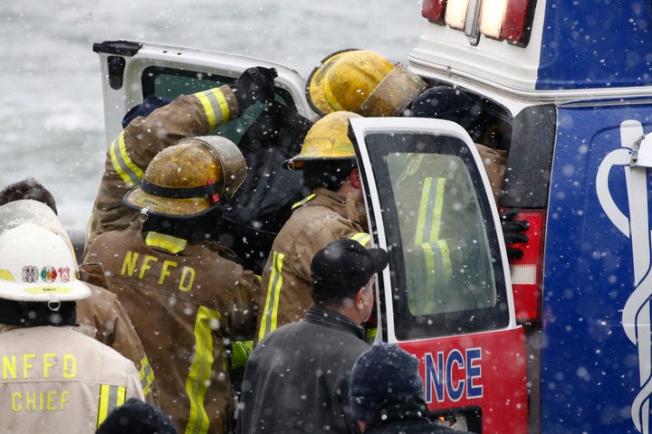 Emergency personnel tend to the person pulled from the submerged vehicle.