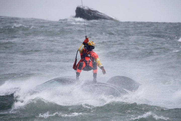 A U.S. Coast Guard diver is lowered from a helicopter to pull a body from a submerged vehicle stuck in rushing rapids just yards from the brink of Niagara Falls on Wednesday.