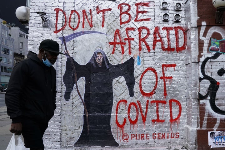 Un hombre pasa por delante de un mural del artista 'Pure Genius' que muestra al expresidente de EEUU, Donald Trump, vestido de la Muerte y con la leyenda 'No temáis al covid'. En Nueva York, 2020.
