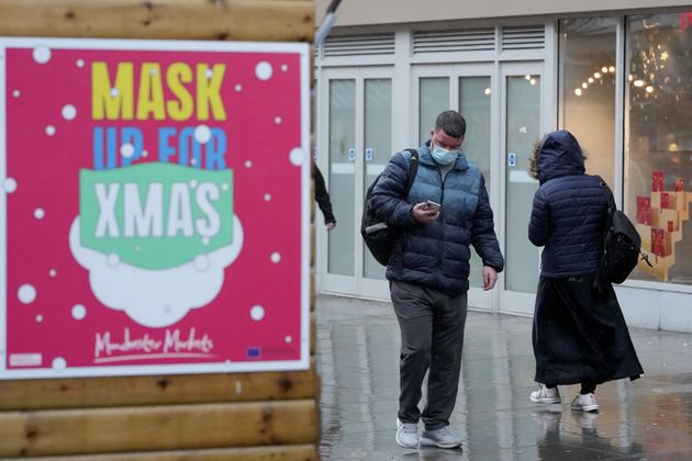 Christmas shoppers walk a past a sign saying 'Mask Up For Christmas