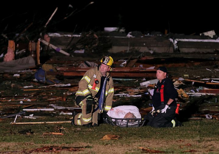 Firefighters wait for help to carry out a person who was found in a debris field injured when a tornado ripped a house off its foundation along Highway F at the intersection of Stub Road in St. Charles County, Mo., Friday, Dec. 10, 2021. (David Carson/St. Louis Post-Dispatch via AP)