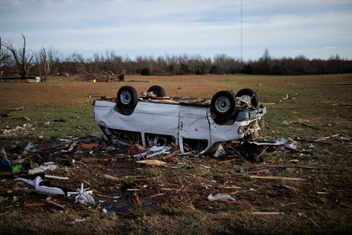 Una camioneta de pasajeros volcada descansa en un campo vacío en un vecindario rural que fue devastado por un tornado en Mayfield, Kentucky.