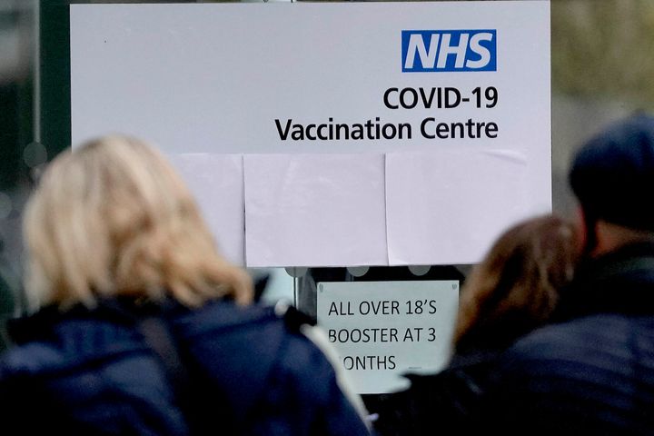 Πολιτες σε ουρά για να εμβολιαστούν στο Λονδίνο, στις 13 Δεκεμβρίου 2021. Ο Τζόνσον λέει ότι η χώρα βρίσκεται προ νέου κύματος κρουσμάτων λόγω της παραλλαγής Ομικρον και καλεί τους Βρετανούς να λάβουν τρίτη τόση του εμβολίου εσπευσμένα. (AP Photo/Frank Augstein)