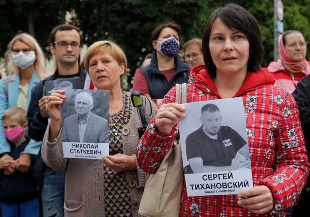 People hold portraits of arrested opposition figures Syarhei Tsikhanouski and Nikolai Statkevich during...