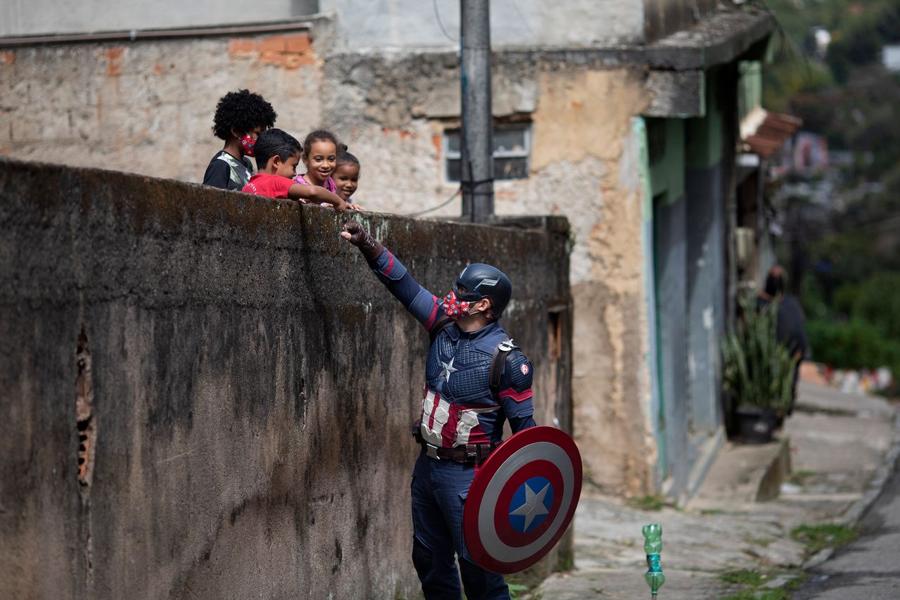 Μέλος της στρατιωτικής αστυνομίας, ντυμένος ως υπερήρωας «Captain America», παροτρύνει μικρά παιδιά να τηρούν τα μέτρα κατά του κορονοϊού - Ρίο Ντε Τζανέιρο, Βραζιλία (15/4/2021)