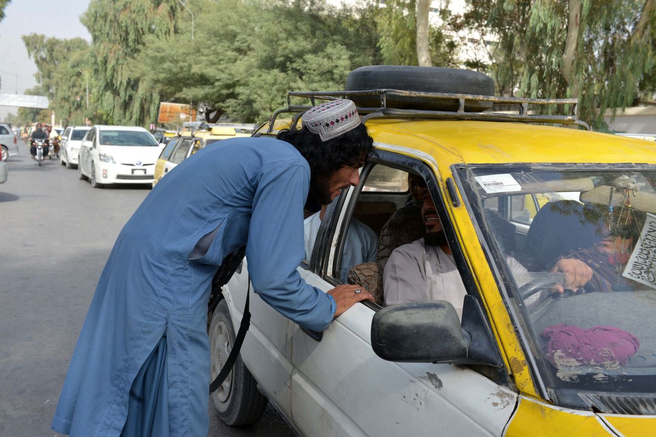 A member of the Taliban talks with a driver at a security checkpoint in Kandahar city, Afghanistan.