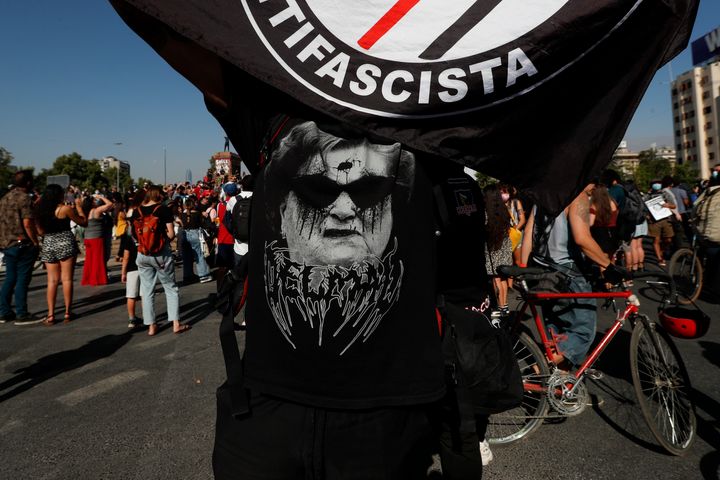Un hombre con bandera antifascista y camiseta diabólica de Lucia Hiriart, en una protesta ayer, en Santiago de Chile. 