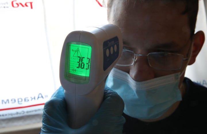 Una persona toma la temperatura a otra.
