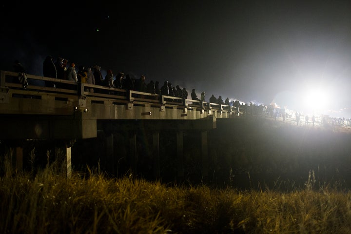 Dakota Access protesters stand their ground on the bridge between Oceti Sakowin Camp and County Road 134 in North Dakota on Nov. 20, 2016, while being sprayed with water cannons and tear gas — paintballs, rubber bullets and sound cannons were also used. The protesters built a fire to stay warm in 26-degree weather while also being soaked by police.