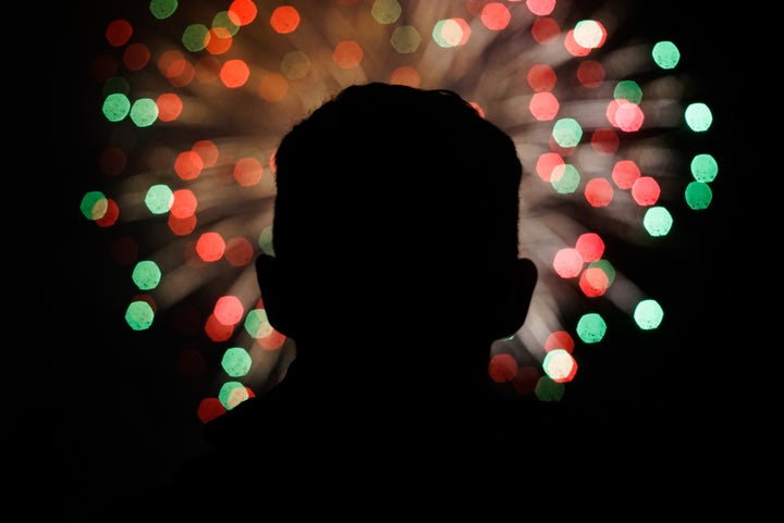Un hombre mira hacia unos fuegos artificiales.