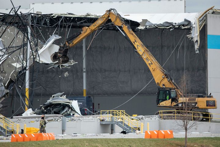 Crews use an excavator to pull down pieces of the damaged roof during search and rescue operations at the Amazon distribution center on Dec. 11.