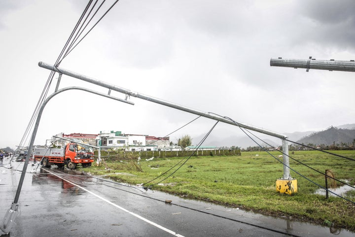 A fallen electric pylon blocks a road while a destroyed truck lies idle in Surigao City.