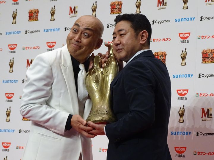 優勝トロフィーを抱く長谷川雅紀さん（左）と渡辺隆さん