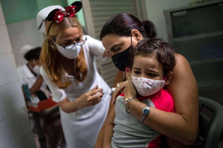 Μητέρα κρατάει την κόρη της που δέχεται δόση του εμβολίου Soberana-02 για COVID-19 στην Αβάνα της Κούβας στις 16 Σεπτεμβρίου 2021. Η Κούβα άρχισε τον εμβολιασμό σε παιδιά από ηλικίας 2 ετών και άνω με τα εμβόλια που εξέλιξε η ίδια χώρα. (AP Photo/Ramon Espinosa)