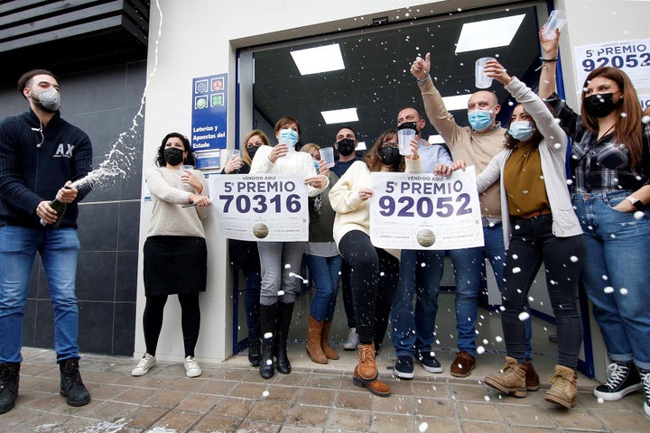 Trabajadores y vecinos de la administración número 3 de Manises, sita en la calle Maestro Guilen, celebran la venta de dos de los quintos premios, el número 92.052 y el 70.316