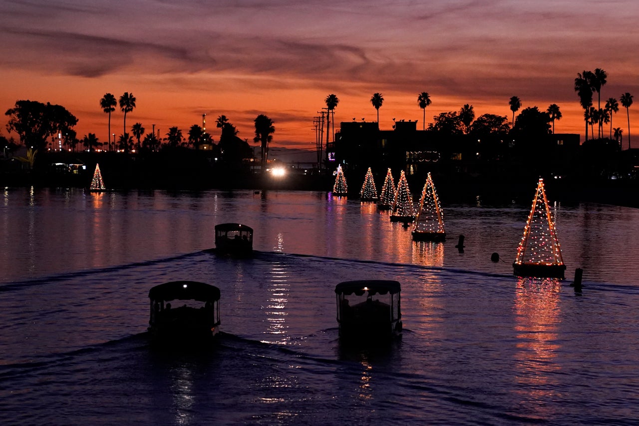 Boats make their way past floating Christmas tree lights on Sunday, in Long Beach, California.