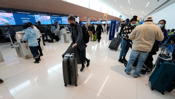 Travelers navigate the check-in area for United Airlines in the terminal of Denver International Airport on Friday, Dec. 24, 2021, in Denver. (AP Photo/David Zalubowski)