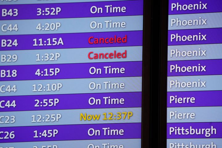 Canceled flights are noted in red on an electronic arrival board in the terminal of Denver International Airport, Friday, Dec. 24, 2021, in Denver. (AP Photo/David Zalubowski)