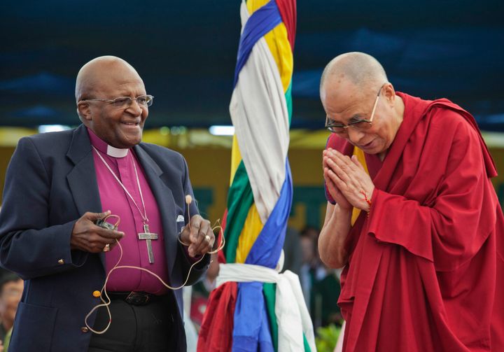 Desmond Tutu, a la izquierda, sostiene un micrófono mientras el líder espiritual tibetano, el Dalai Lama, hace gestos, mientras interactúan con los niños en la Escuela de la Aldea Infantil Tibetana en Dharmsala, India, el jueves 23 de abril de 2015. (Foto AP / Ashwini Bhatia, Archivo)