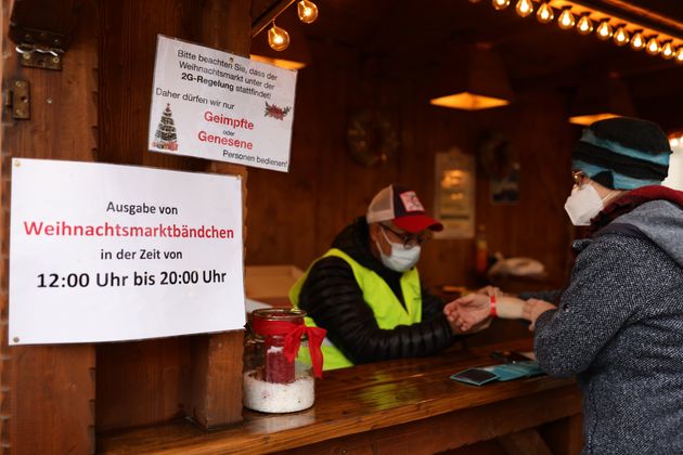 BONN, GERMANY - DECEMBER 14: A woman receives a red wristband after having her vaccination status and...