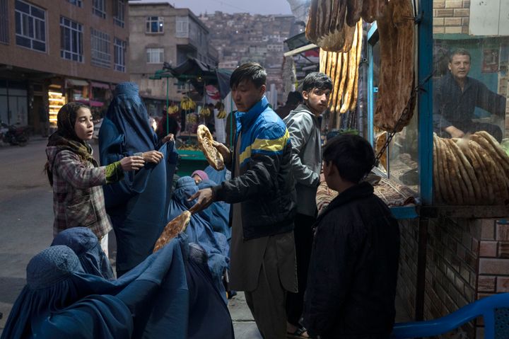 A man disributes bread to Afghan women outside a bakery in Kabul, Afghanistan, on Thursday, Dec, 2, 2021. (AP Photo/Petros Giannakouris)