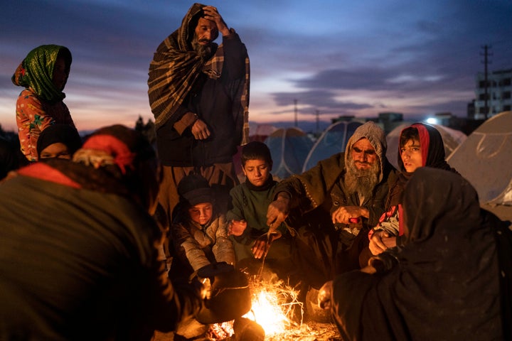 A family warm up next to makeshift fire outside the Directorate of Disaster office where they are camped, in Herat, Afghanistan, Monday, Nov. 29, 2021. (AP Photo/Petros Giannakouris)