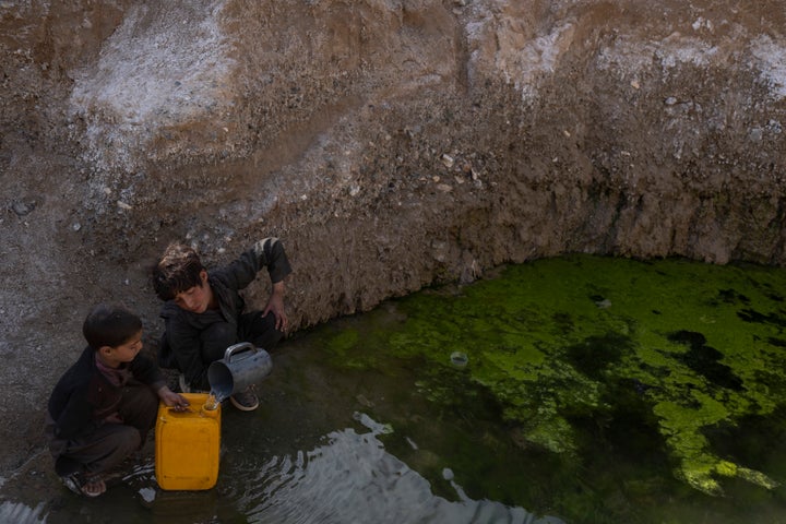 Brothers fill canisters with water from a pool of stagnant water about 3 kilometers (2 miles) far from their home in Kamar Kalagh village outside Herat, Afghanistan, Friday, Nov. 26, 2021. (AP Photo/Petros Giannakouris)