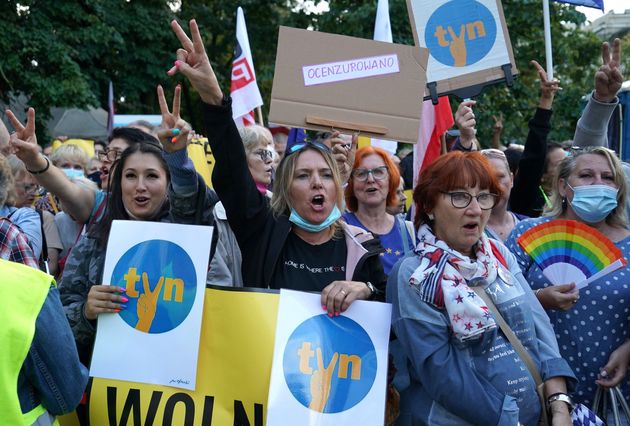 Protesters carry placards with letters from Poland's leading private television station.