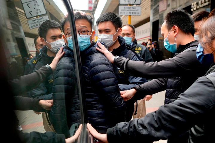 Patrick Lam, center, editor of Stand News, is escorted by police officers into a van after they searched his office in Hong Kong, on Dec. 29, 2021. 