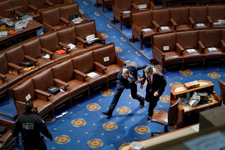A member of the U.S. Capitol Police rushes a lawmaker out of the House Chamber as rioters try to enter the floor and obstruct the certification of Joe Biden's 2020 presidential win.