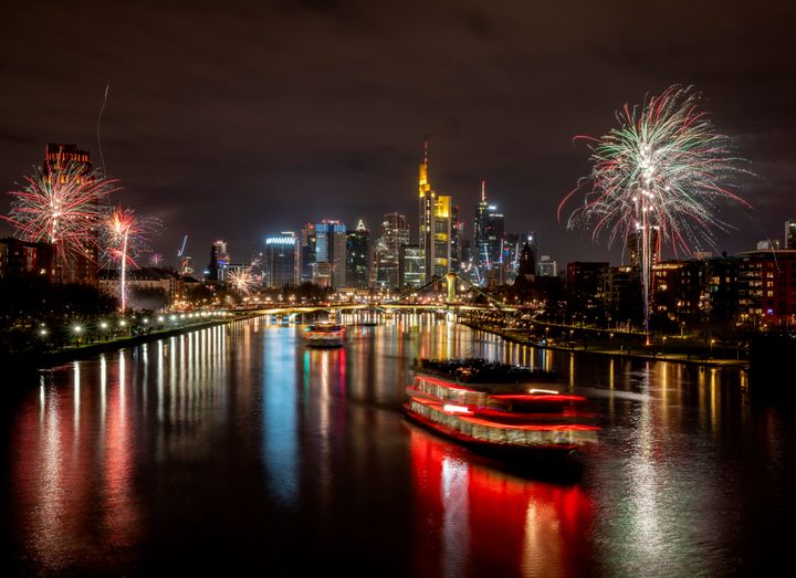 Party boats cruise over the river Main with only a few fireworks near the buildings of the banking district in Frankfurt, Germany, early on Saturday, Jan. 1, 2022. (AP Photo/Michael Probst)