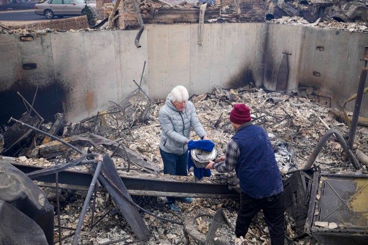 John Peer finds a couple of plates as he looks through the rubble of his fire-damaged home after the Marshall Wildfire in Louisville, Colo., Friday, Dec. 31, 2021.