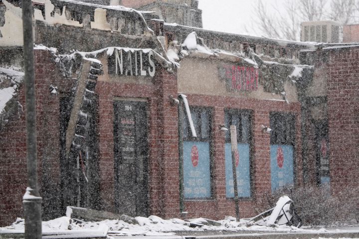 Snow falls on a row of small businesses burned by wildfires after they ripped through a development on Dec. 31, 2021, in Louisville, Colorado.